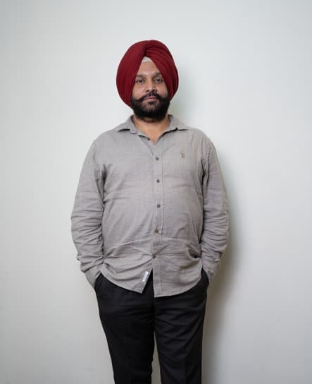 Dr. Arvinder Singh Bali, BAMS, standing in a grey shirt against a plain wall